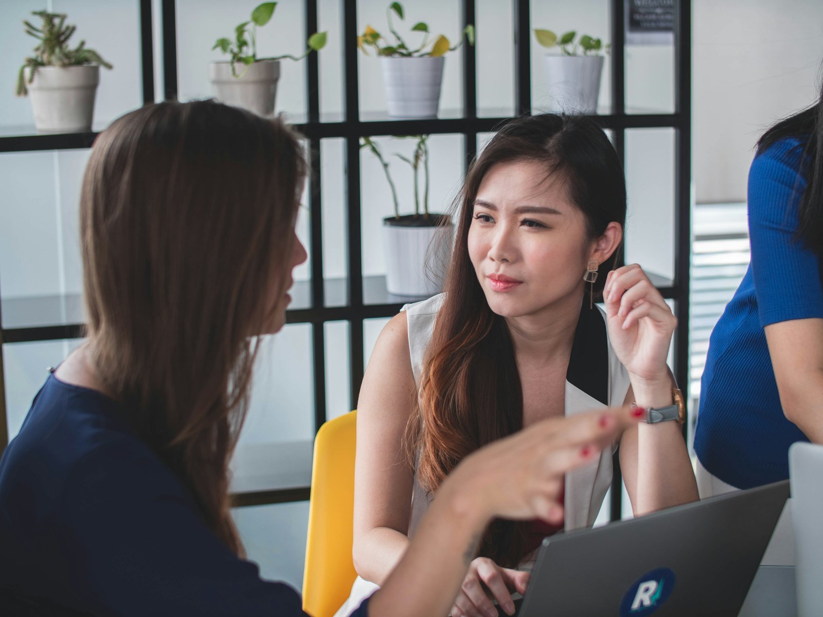 Two women talking through a question together at a workspace