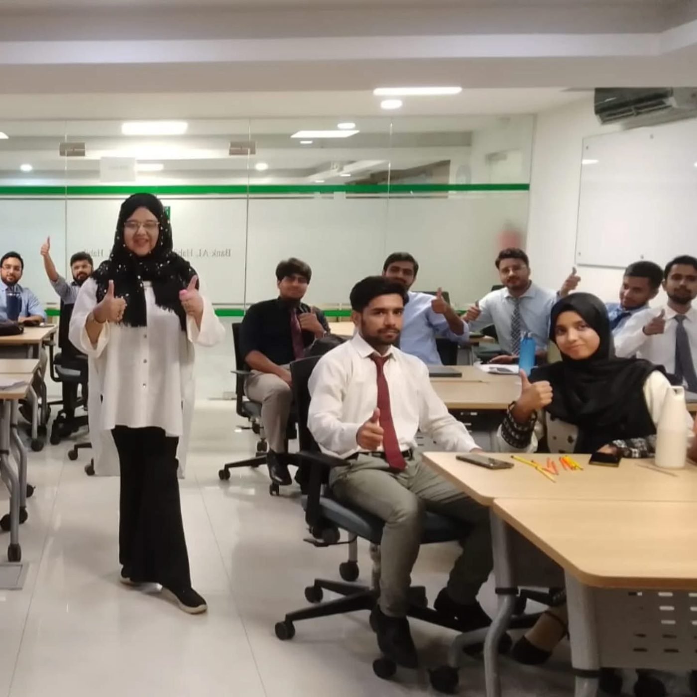 A trainer standing at the front of a Bank Al Habib training room as a group of trainee officers give a thumbs-up from their desks
