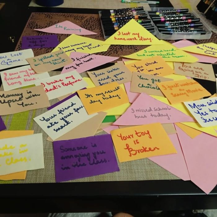 Dozens of handwritten cards spread across a table describing everyday situations for children to respond to