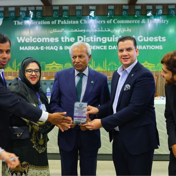 A commemorative shield being handed over between guests on stage at a Federation of Pakistan Chambers of Commerce and Industry event