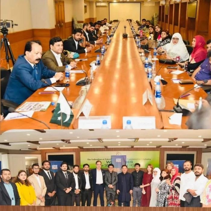 A long conference table lined with delegates above a group photograph of the same delegation
