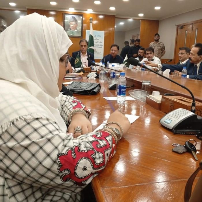 Participants seated along a long polished table with conference microphones during a policy roundtable