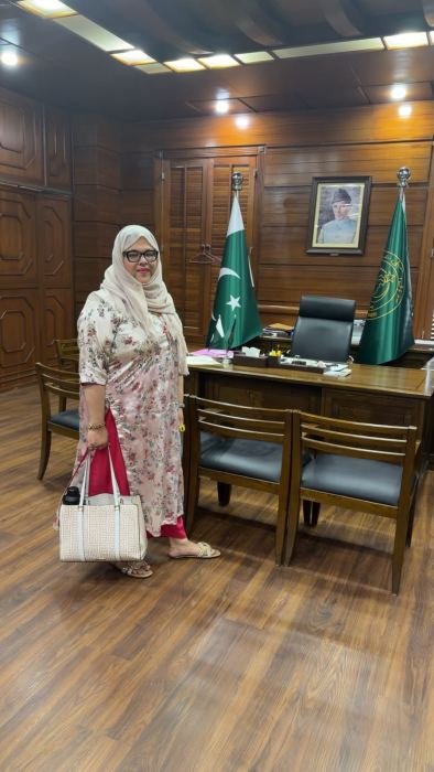 A visitor standing in a wood-panelled office at the Sindh Assembly beside the national and provincial flags
