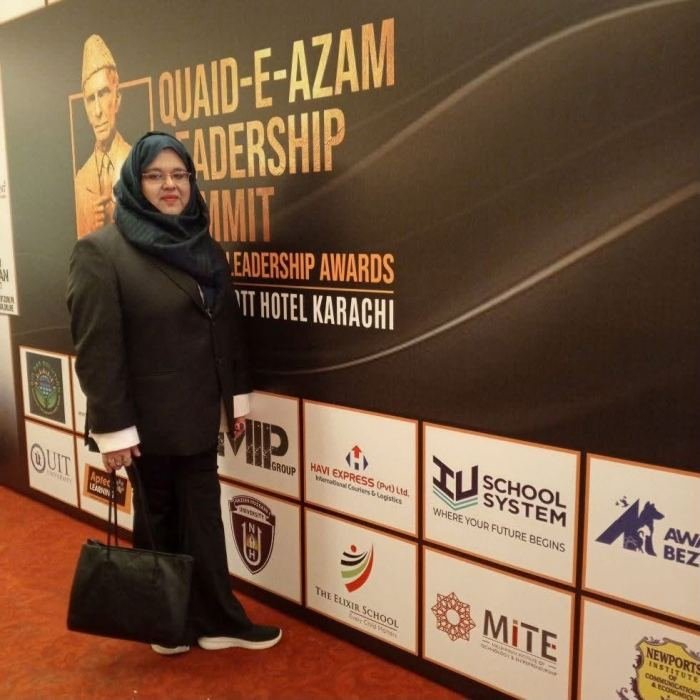 A guest standing beside the Quaid-e-Azam Leadership Summit and Leadership Awards backdrop