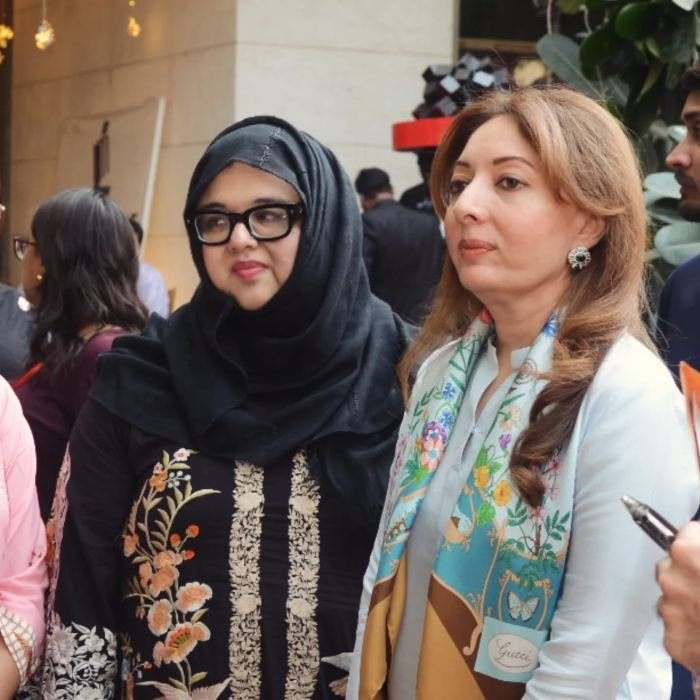 Two women standing together among guests at a professional networking event