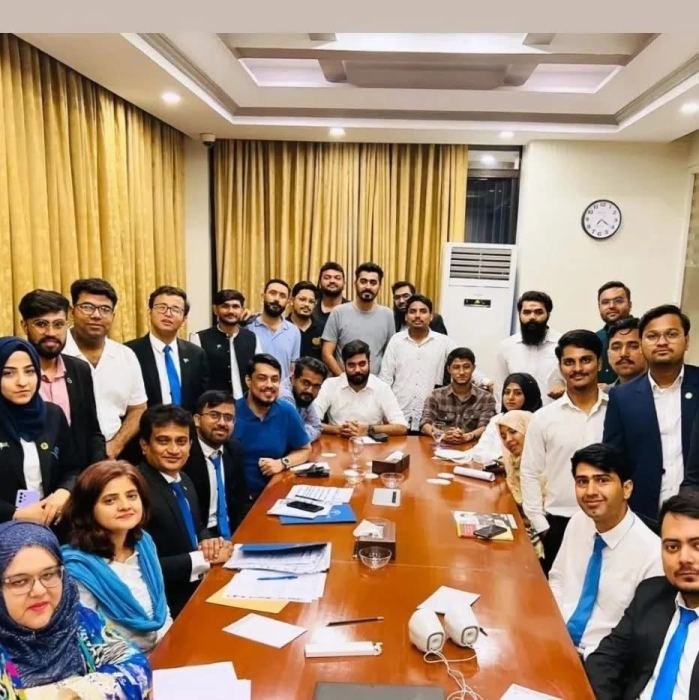 A large group of young participants gathered around a boardroom table for a group photograph at the end of a programme