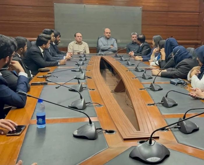 Delegates seated on both sides of a long committee table facing the chair during a session at the Sindh Assembly