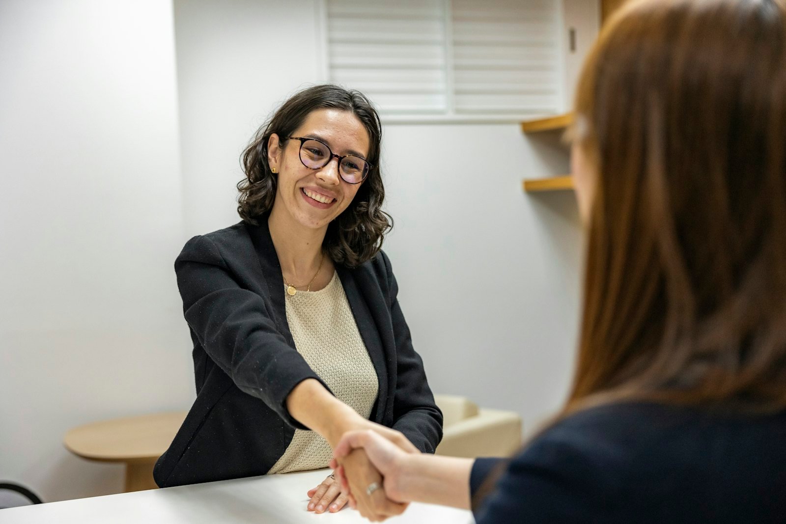 A candidate shaking hands with an interviewer across a desk after a mock interview