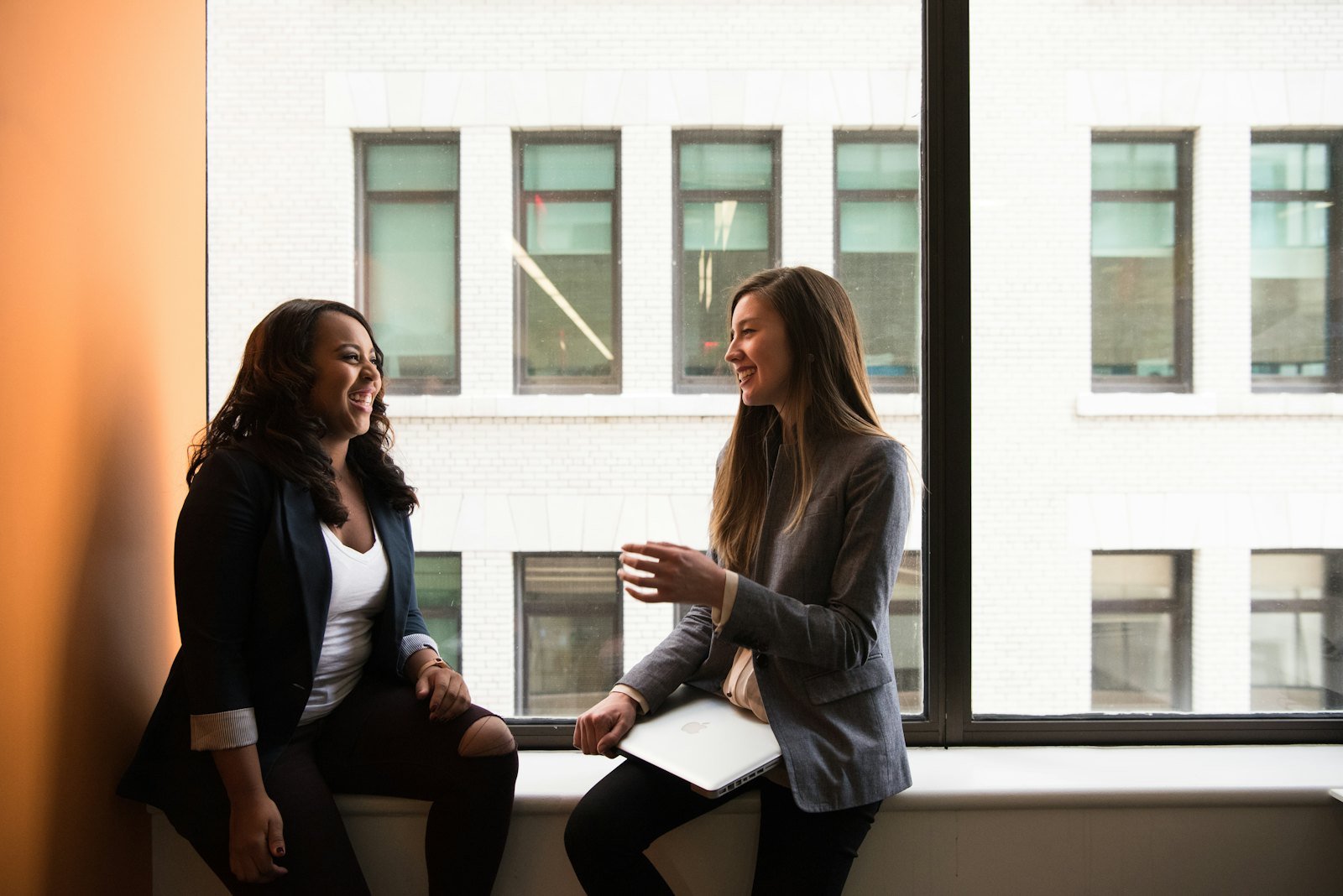Two women talking warmly by a window during a relaxed mindset session